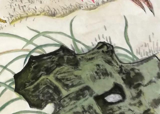 A blue-green rock, dense with moss dots, and blades of grass.