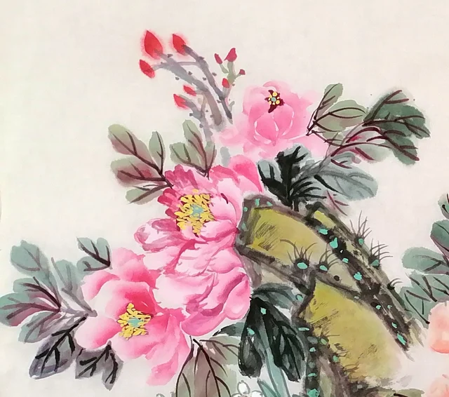Pink peonies opening against a rock at the left.