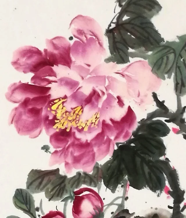A peony in shades of rouge behind the rock.