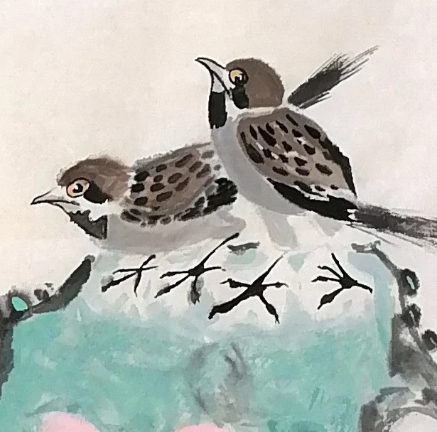 Two sparrows on the rock, one crouching, one looking back.