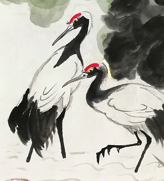 The pair of red-crowned cranes, one standing, one stepping forward.