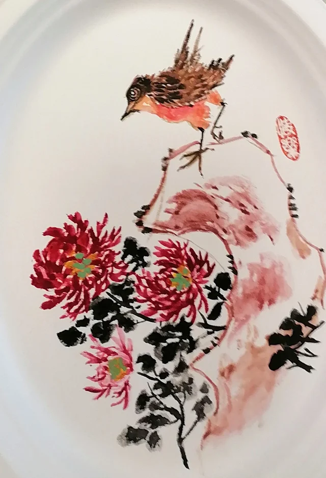 The bird on the rock above red chrysanthemums.