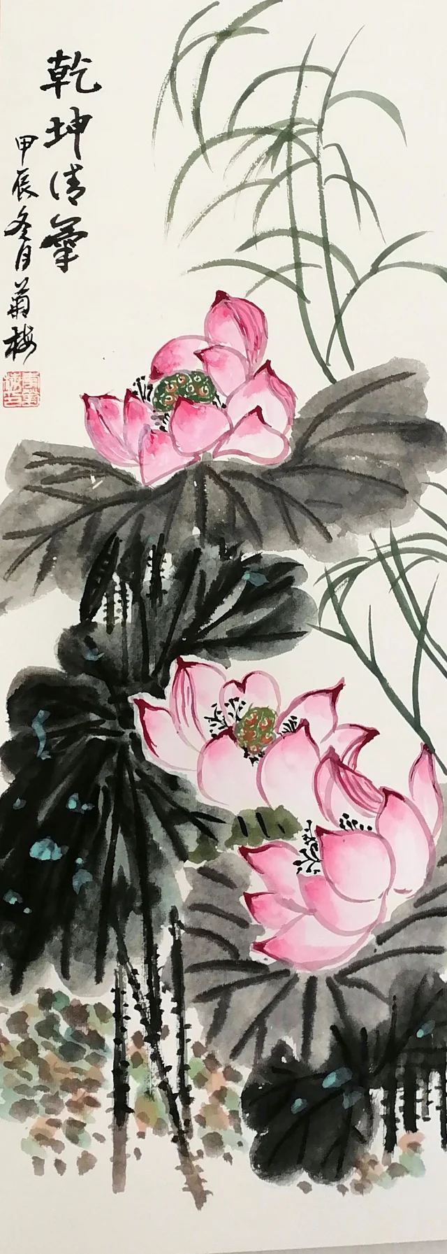 A tall narrow painting on card of two pink lotuses among large dark ink leaves, with fine reeds leaning in from the right; calligraphy at the upper left.