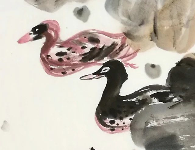 A pair of ducks swimming beneath the leaves.
