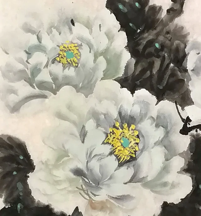 The large bloom on the left, whiter against dark leaves.