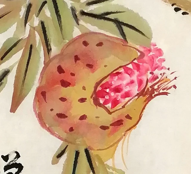 The pomegranate at the left, its seeds glistening.
