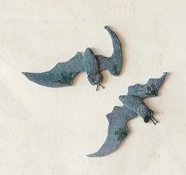 Two blue-gray bats, cut from patterned cloth.
