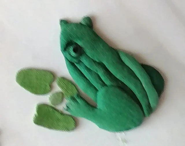 The padded green frog, raised like a small relief.