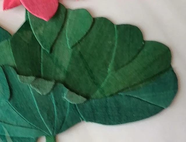 A leaf pieced from wedges of green cloth, the gaps reading as veins.