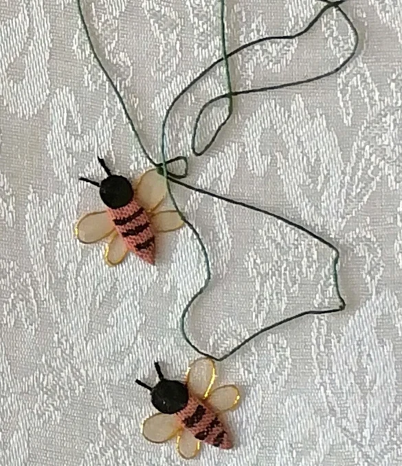 Two bees with gold-edged wings among the thread tendrils.
