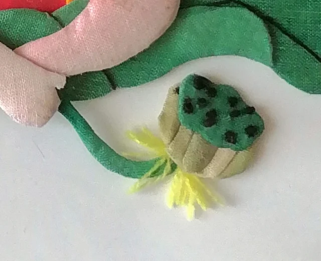 The lotus pod, black seeds on green, with yellow thread stamens.