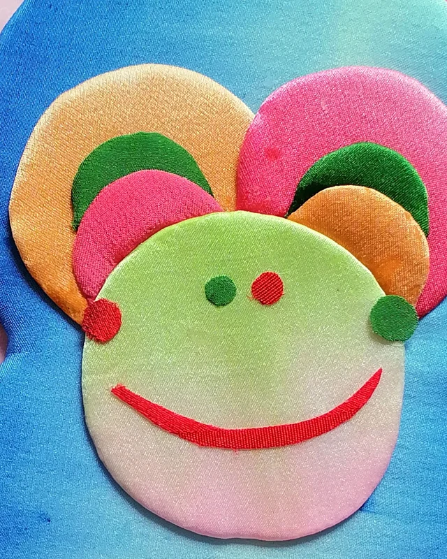 The smiling face: overlapping orange and pink disks and a red cloth smile.